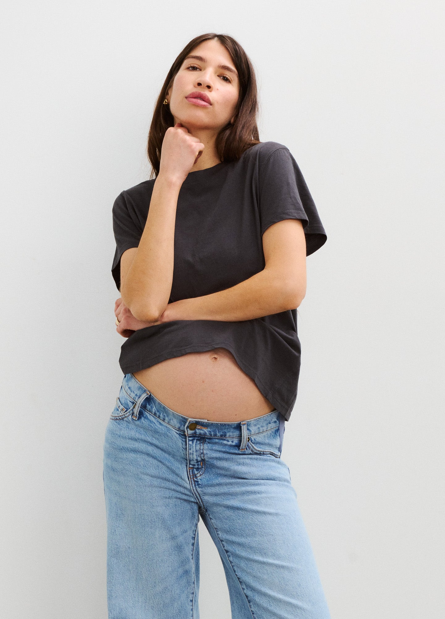 Black cotton crew neck maternity t-shirt with short sleeves, worn with light blue jeans, relaxed fit.