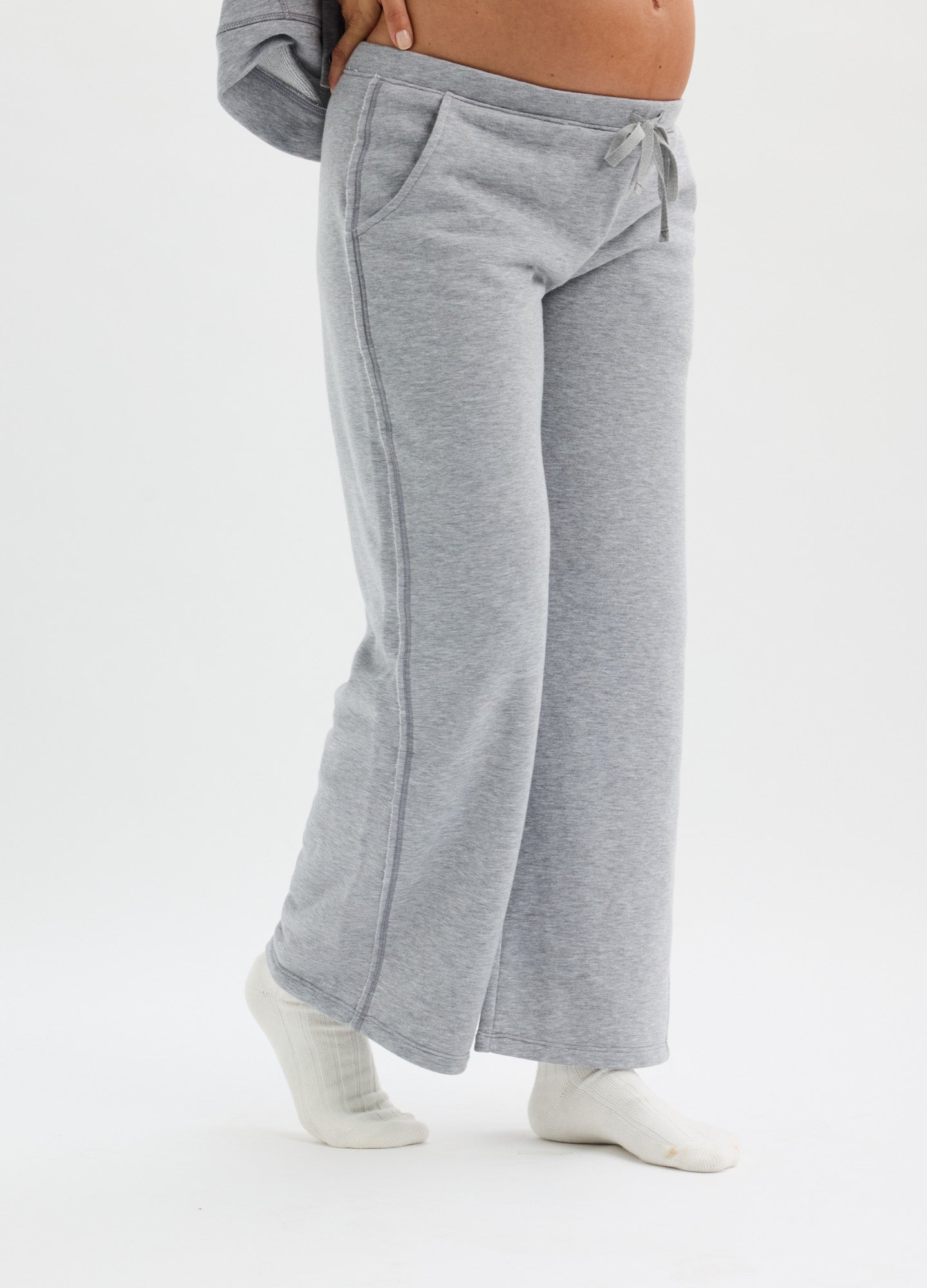 Light gray maternity sweatpants with wide legs and side pockets, designed for pregnant comfort.