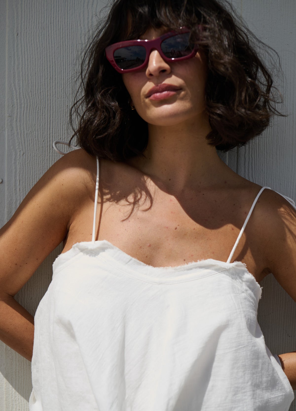 White lightweight maternity dress with thin spaghetti straps and scalloped neckline, worn by pregnant model.