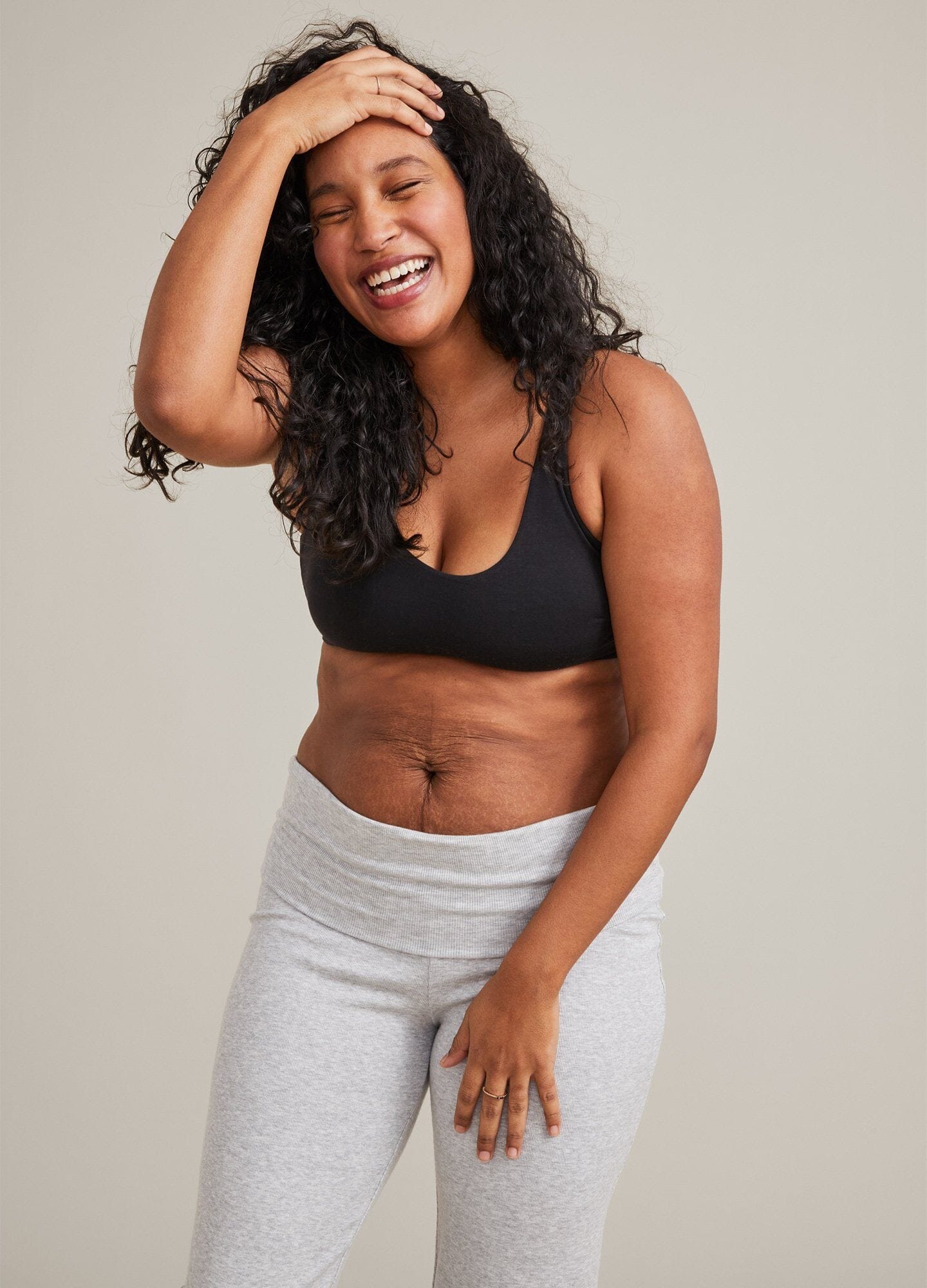 Black seamless maternity bra with wide straps and soft stretch fabric modeled with gray sweatpants.