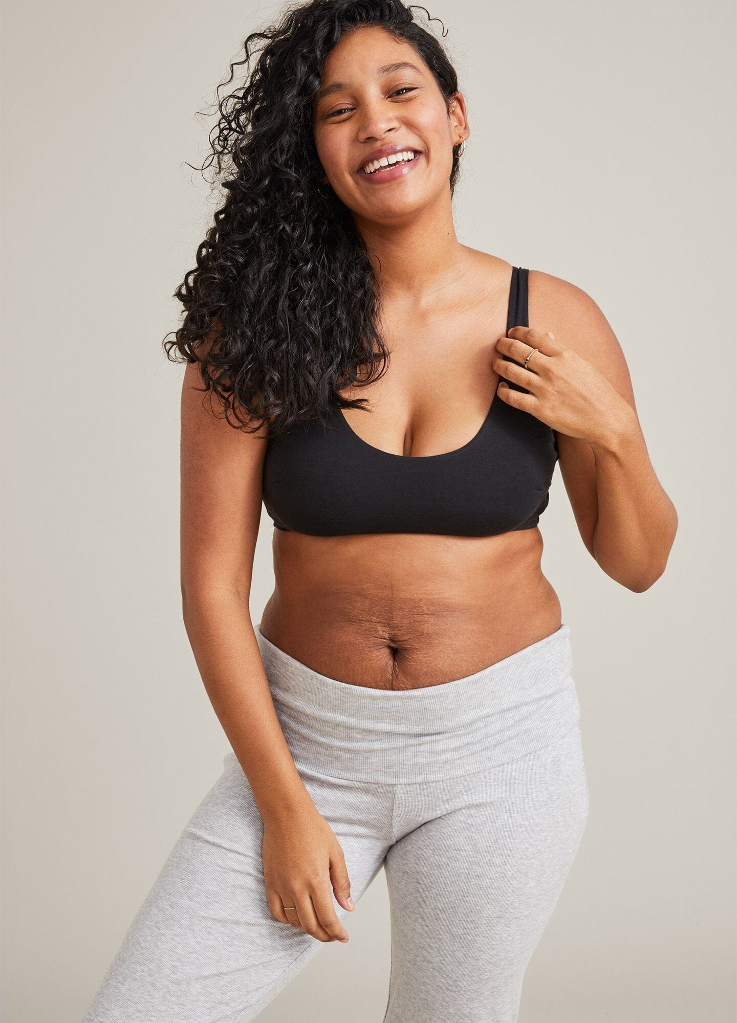 Black seamless maternity bra with wide straps and soft fabric worn by smiling woman.