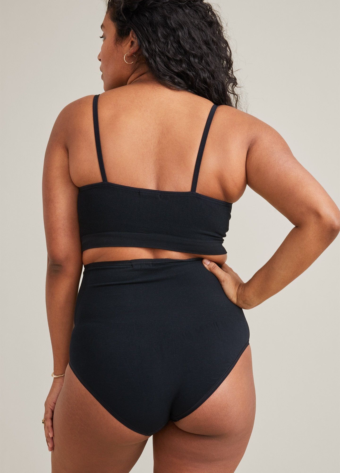 Black maternity pumping bra with adjustable thin straps on pregnant model's back.