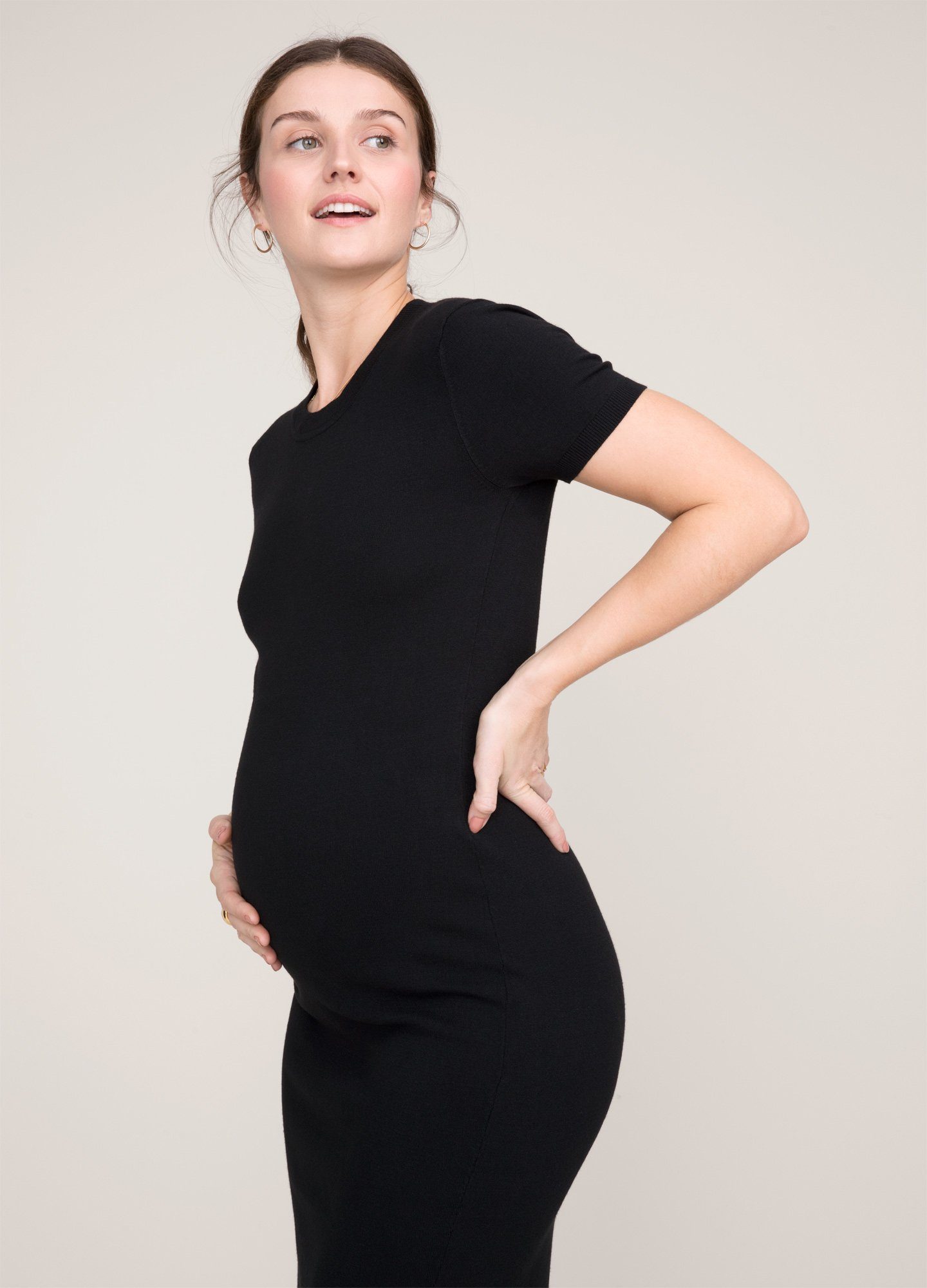 The Eliza Dress POS - Black short-sleeve maternity dress with nursing-friendly design and fitted silhouette, styled with tall black boots.