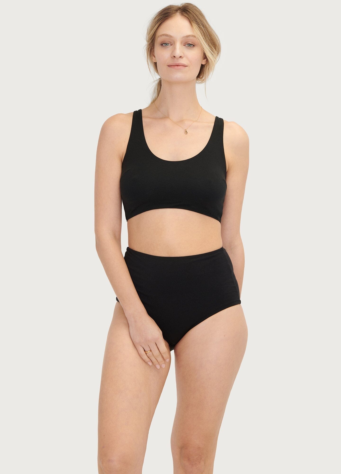 Black seamless maternity bra with wide straps and smooth fabric, modeled with high-waist black briefs.